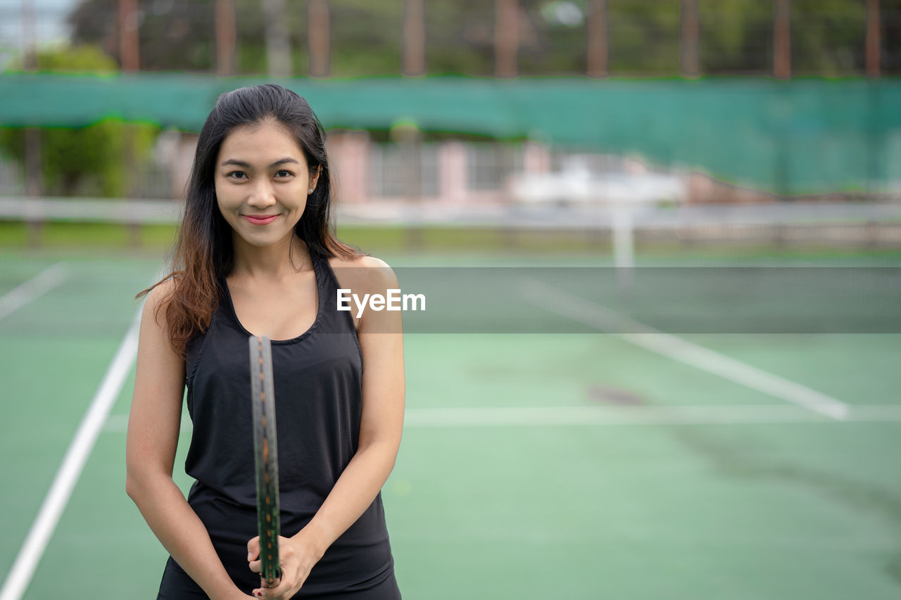 Portrait of smiling tennis player standing in court