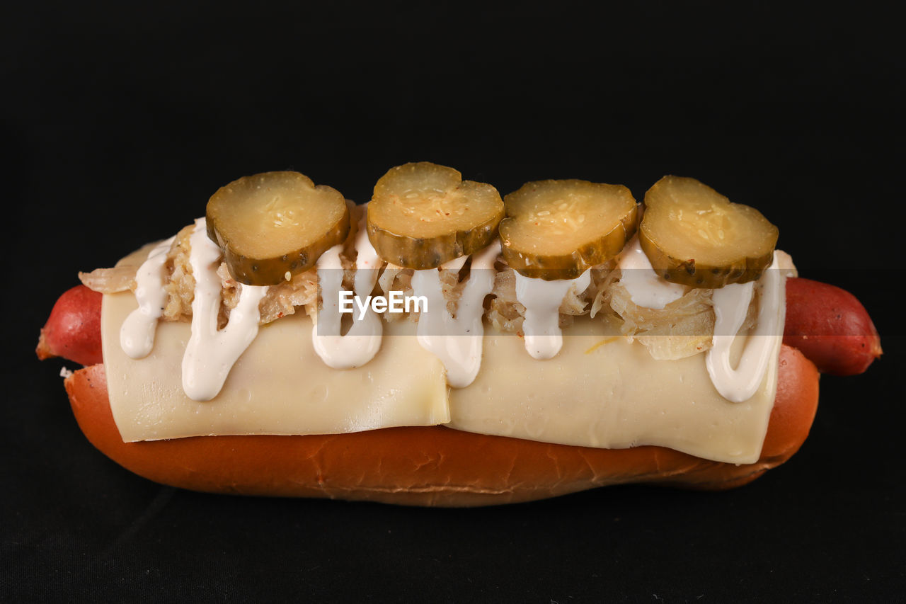 Close-up of hot dog 
on table against black background
