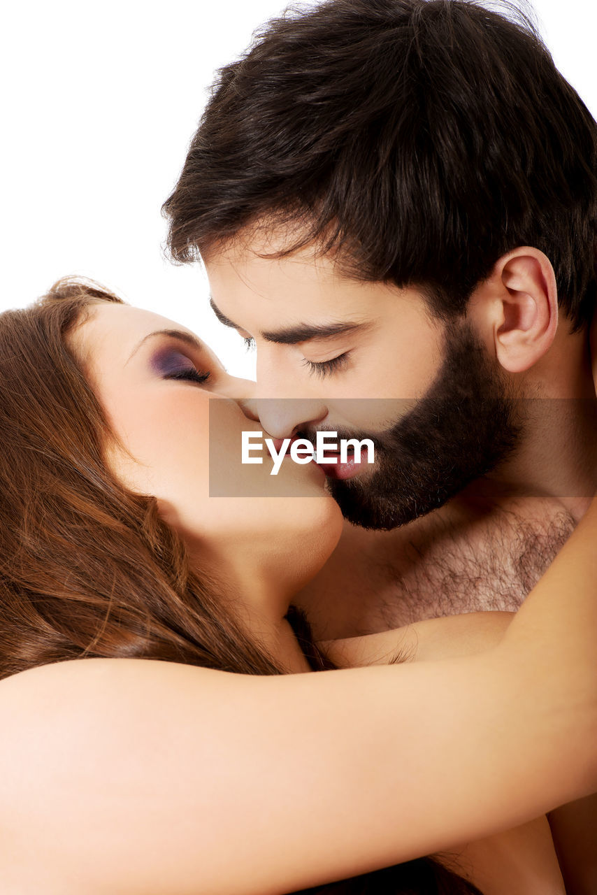 Romantic young couple kissing against white background