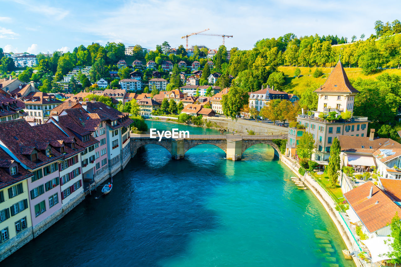 BRIDGE OVER RIVER AMIDST BUILDINGS IN CITY