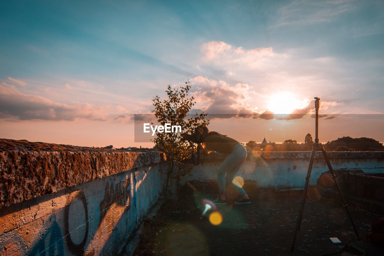 Woman photographing through camera during sunset