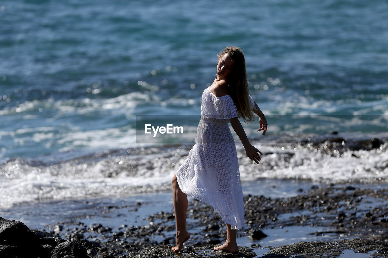 WOMAN STANDING AT BEACH