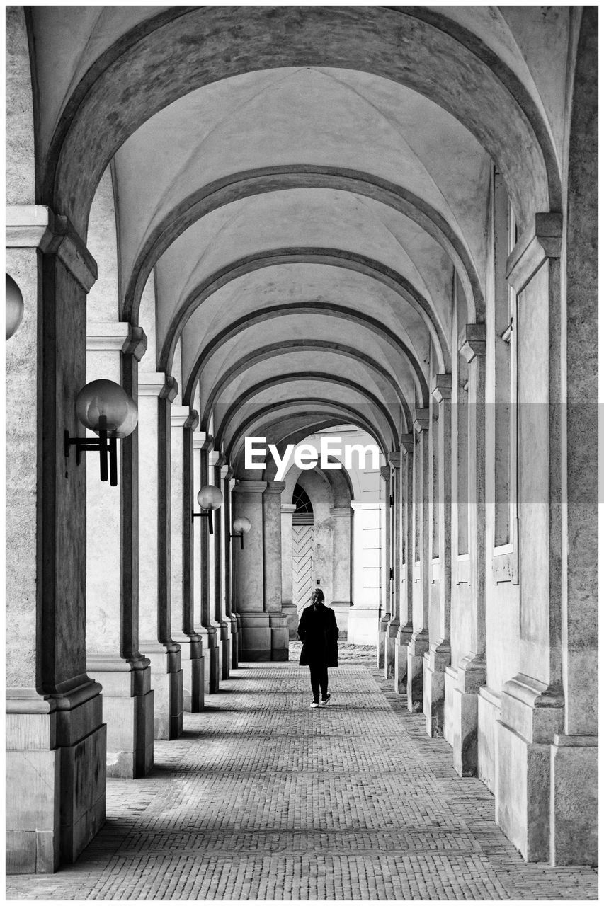 Rear view of man walking in historic building