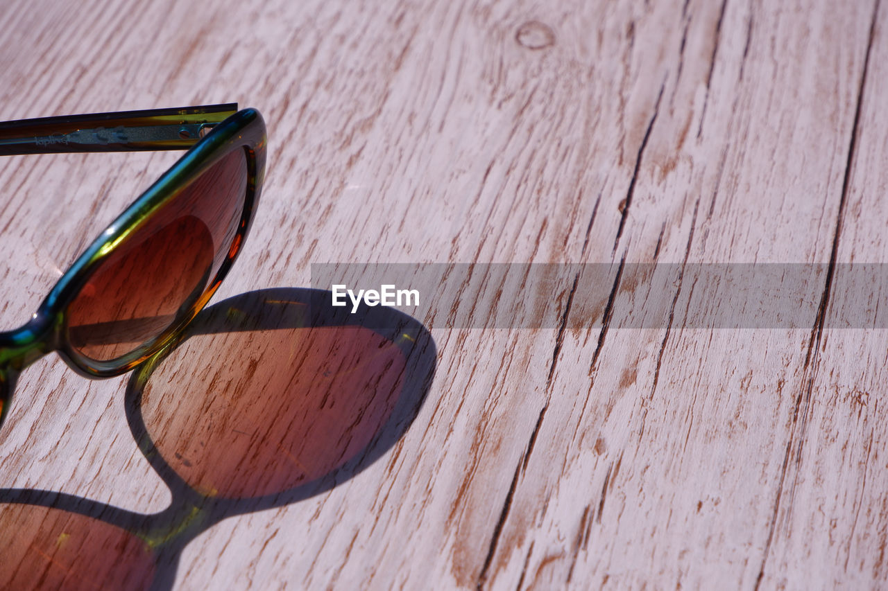 CLOSE-UP OF SUNGLASSES ON WOODEN TABLE