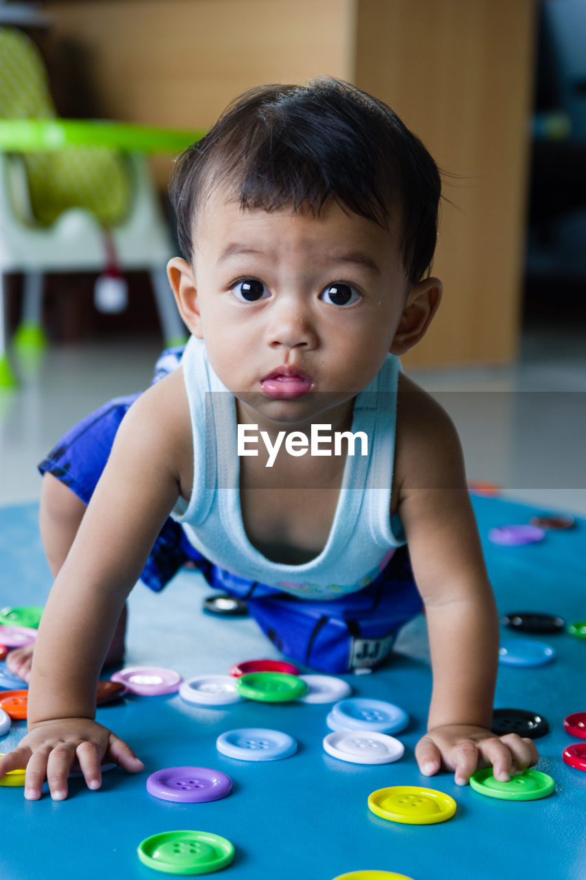 Portrait of baby boy playing with colorful buttons at home