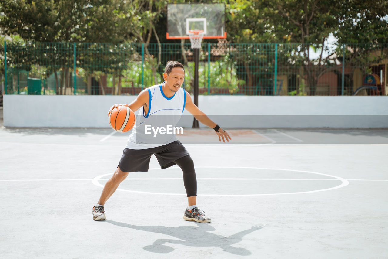 Portrait of man playing with basketball