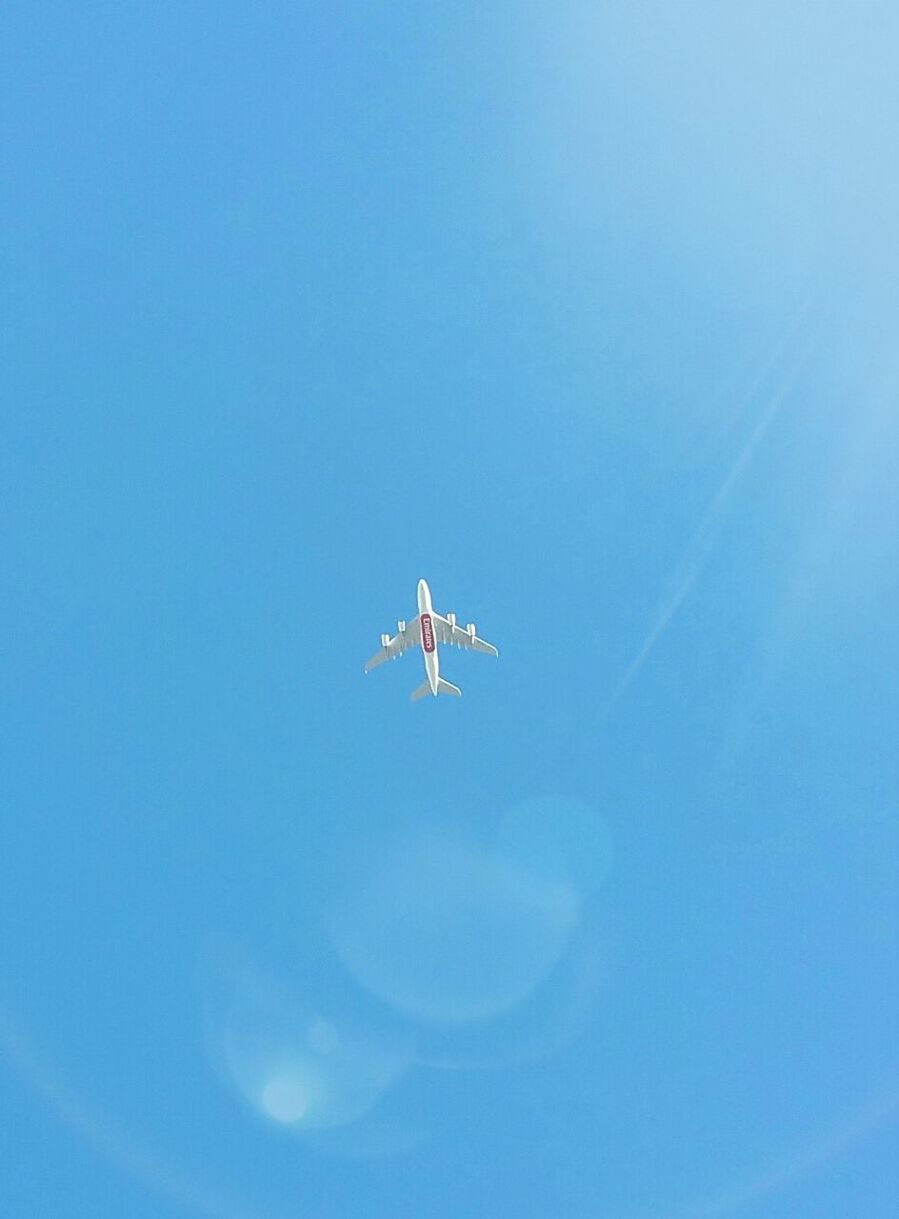 LOW ANGLE VIEW OF AIRPLANE FLYING IN CLEAR BLUE SKY