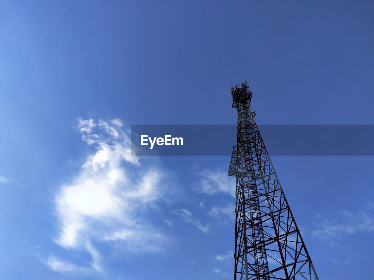 Low angle view of communications tower against blue sky