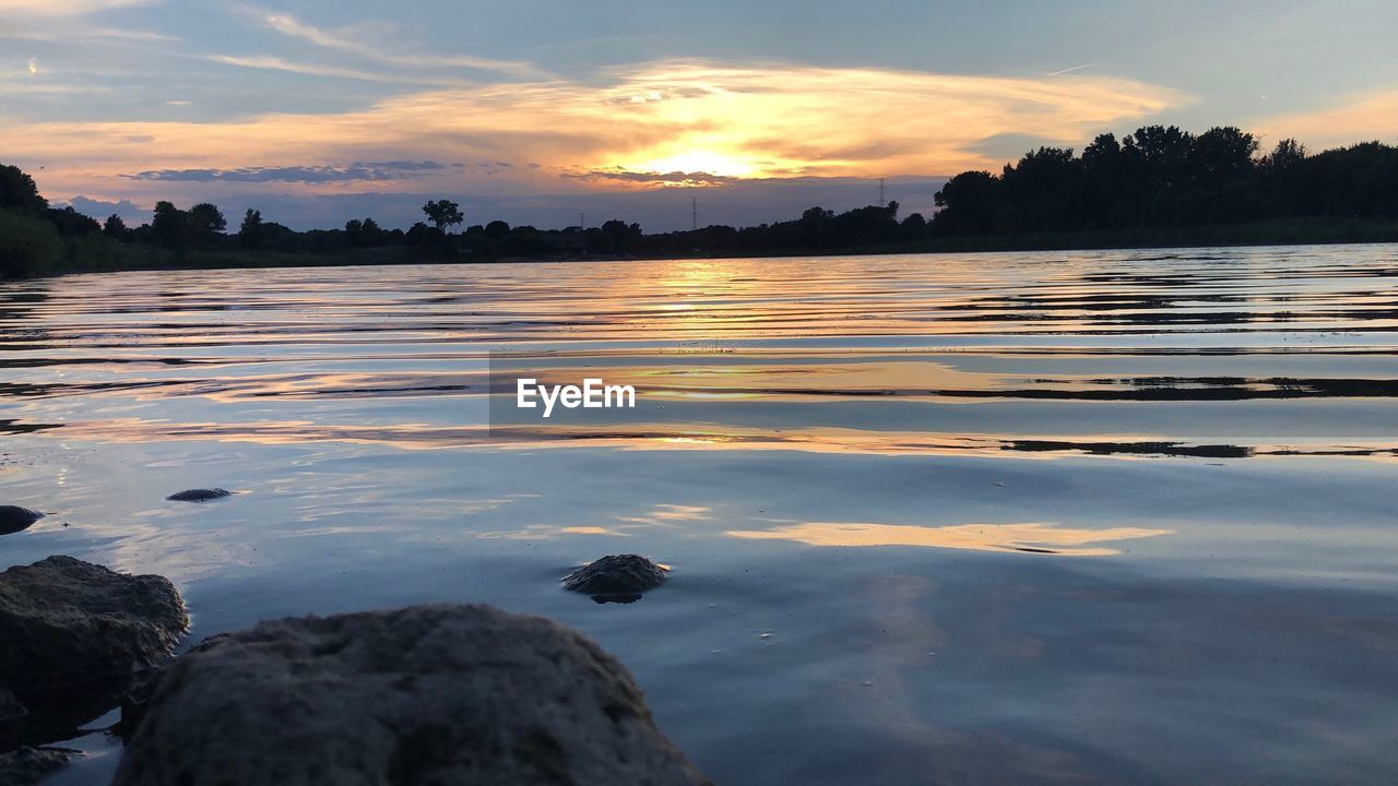 SURFACE LEVEL OF LAKE AGAINST SKY DURING SUNSET