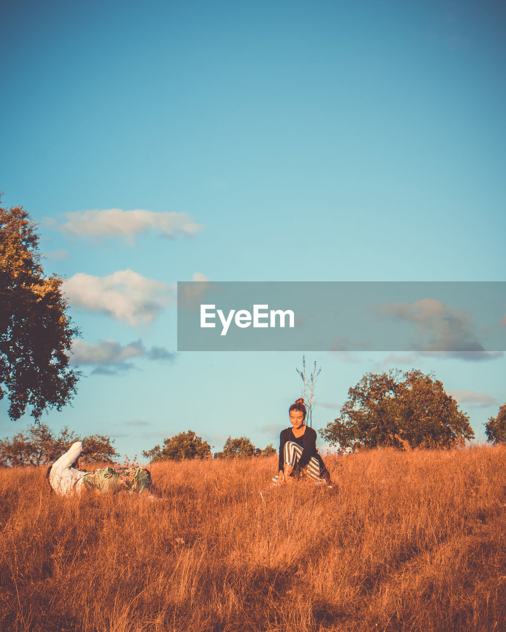 Man photographing woman sitting on field