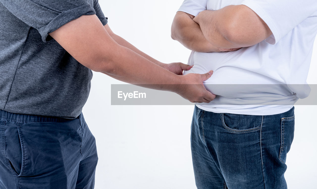 MIDSECTION OF MAN AND WOMAN STANDING AGAINST GRAY BACKGROUND