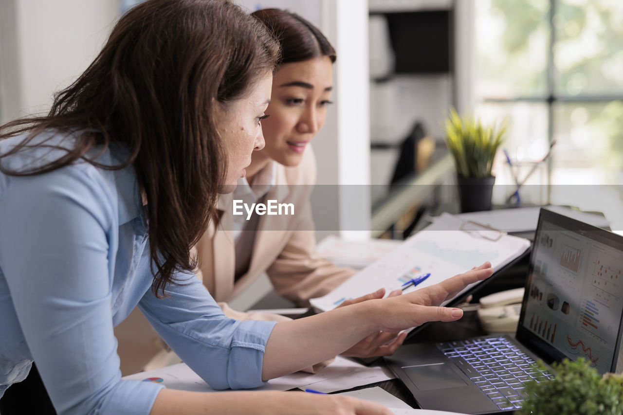 side view of young woman using laptop at office