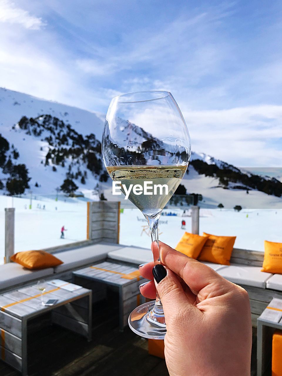 Woman holding champagne flute against snowcapped mountain