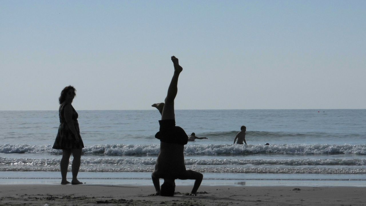 People enjoying at beach against clear sky