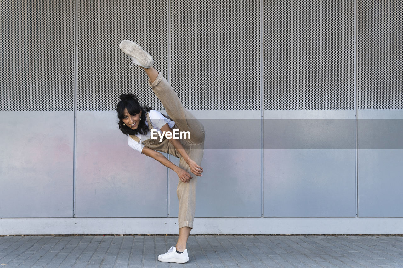 Smiling woman kicking on footpath