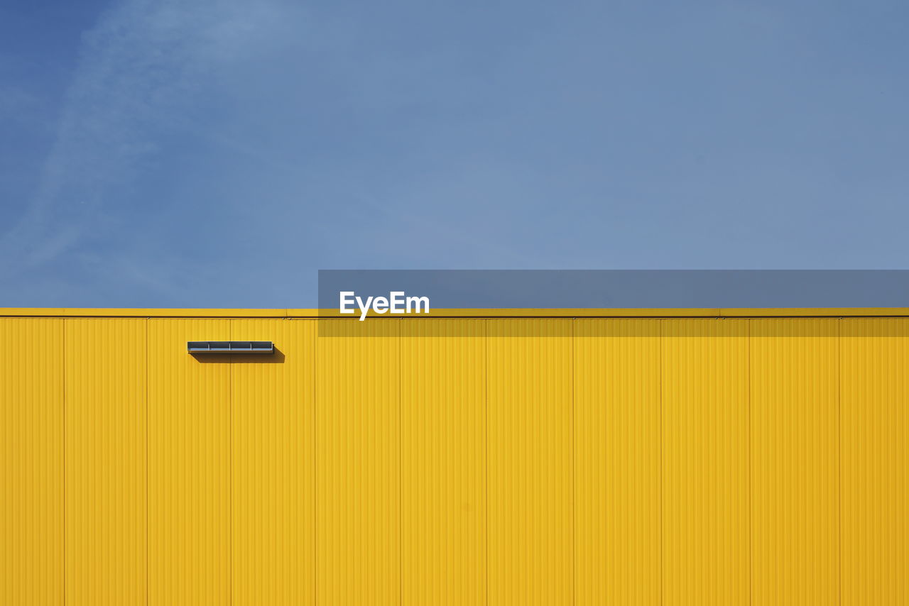 Low angle view of yellow wall against blue sky