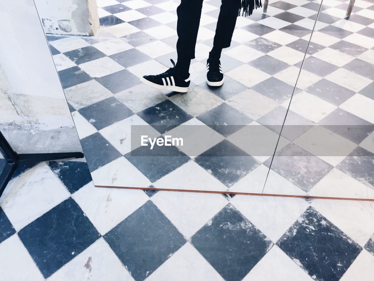 LOW SECTION OF WOMAN STANDING ON TILED FLOOR