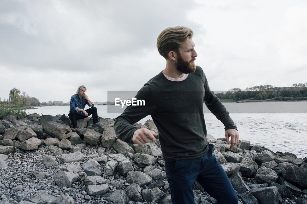 Father and son spending time together, son skipping pebbles