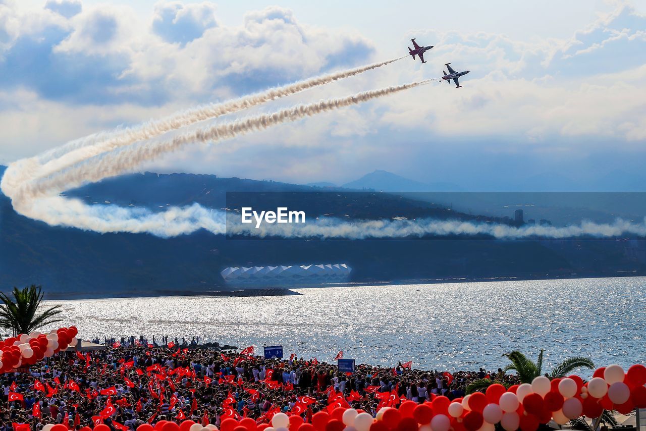 Low angle view of airplanes flying over lake against cloudy sky