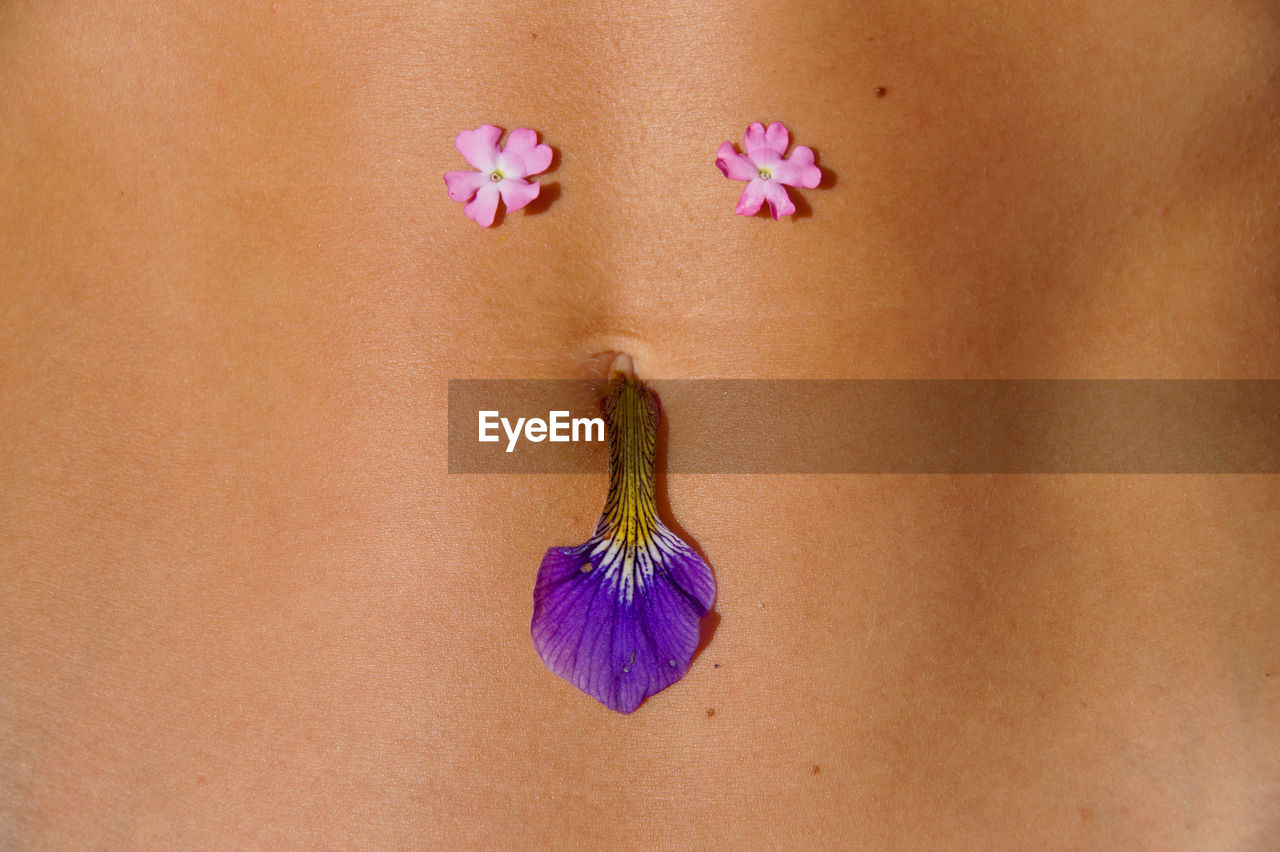 Midsection of woman with flowers on abdomen