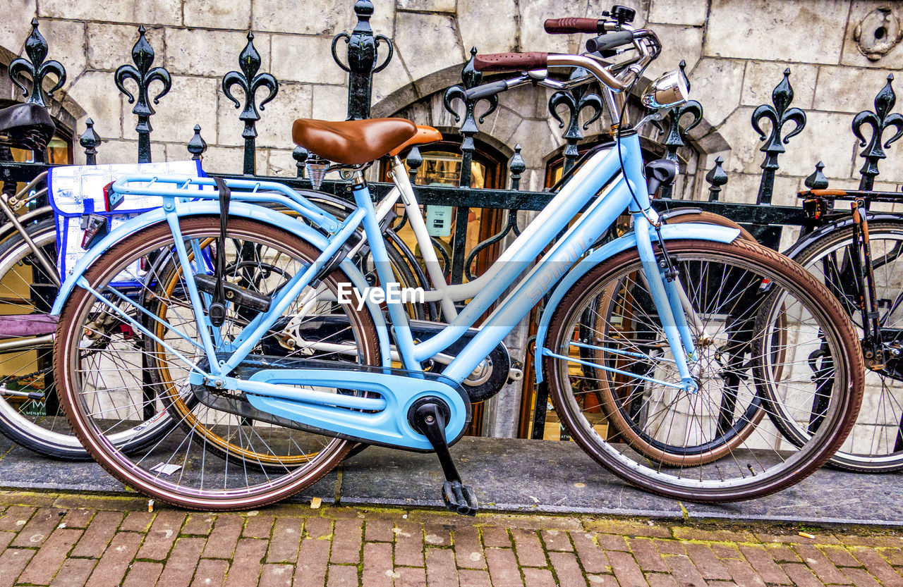 BICYCLE PARKED ON FOOTPATH BY RAILING