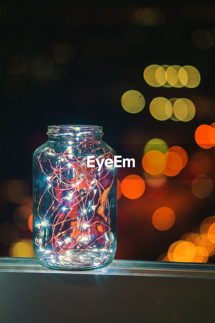 Close-up of illuminated lighting equipment in glass jar on table