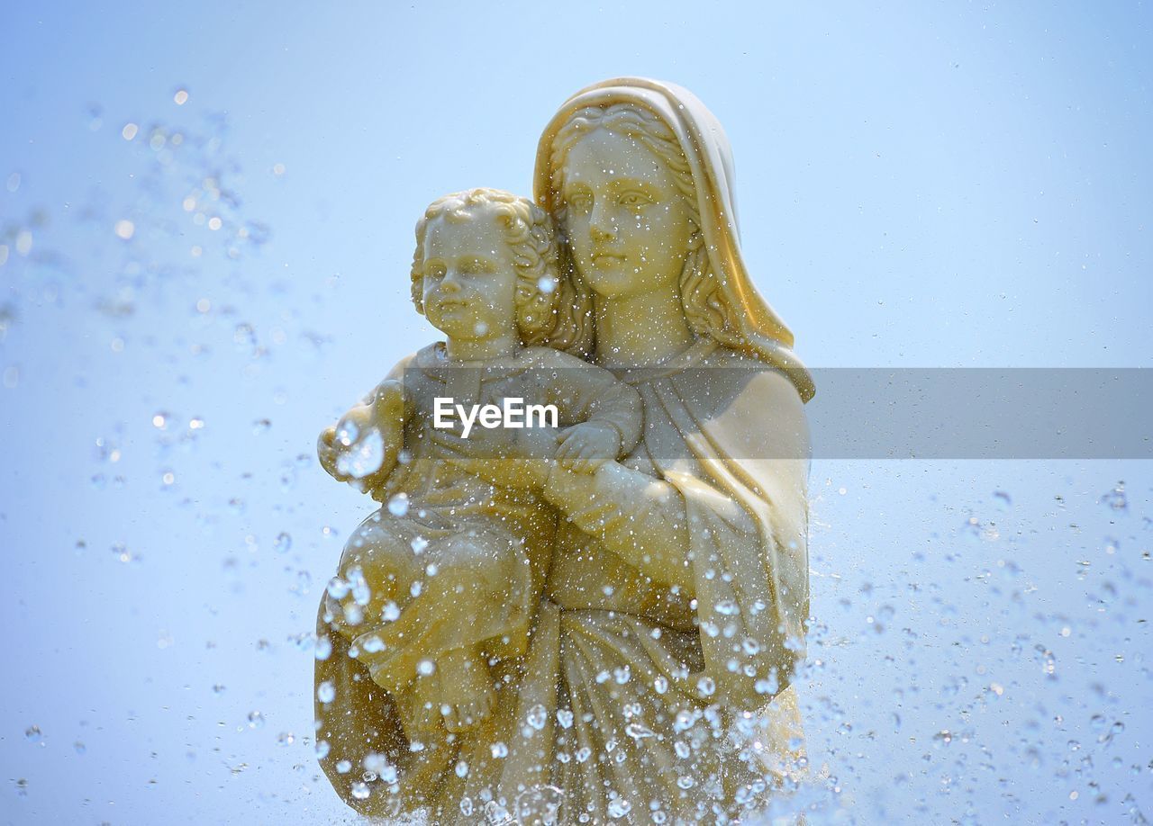 Close-up of statue of mary and jesus against blue background