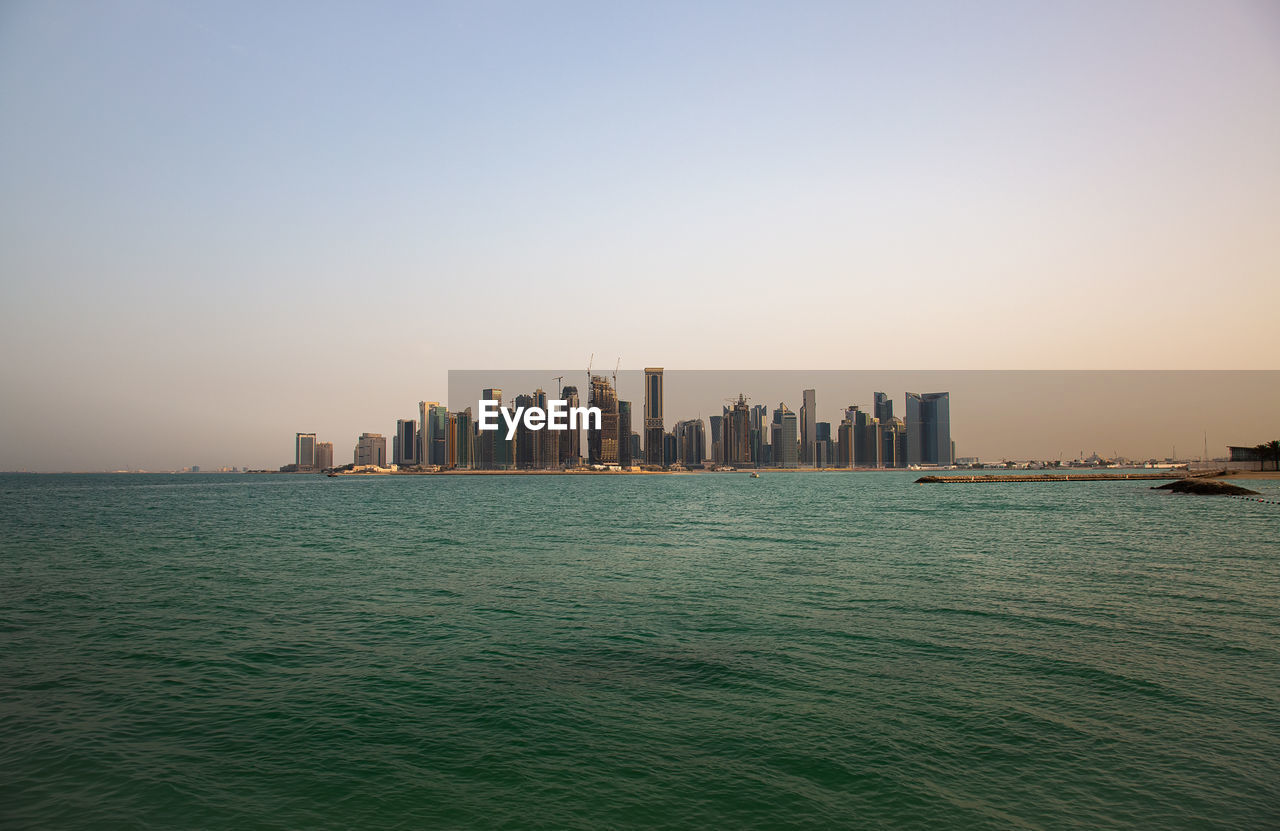 Scenic view of sea and buildings against clear sky