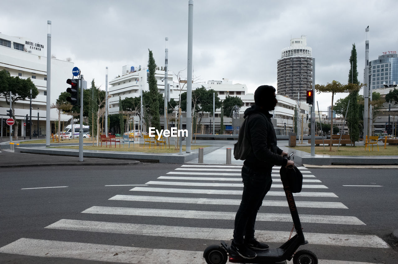 REAR VIEW OF MAN CROSSING ROAD