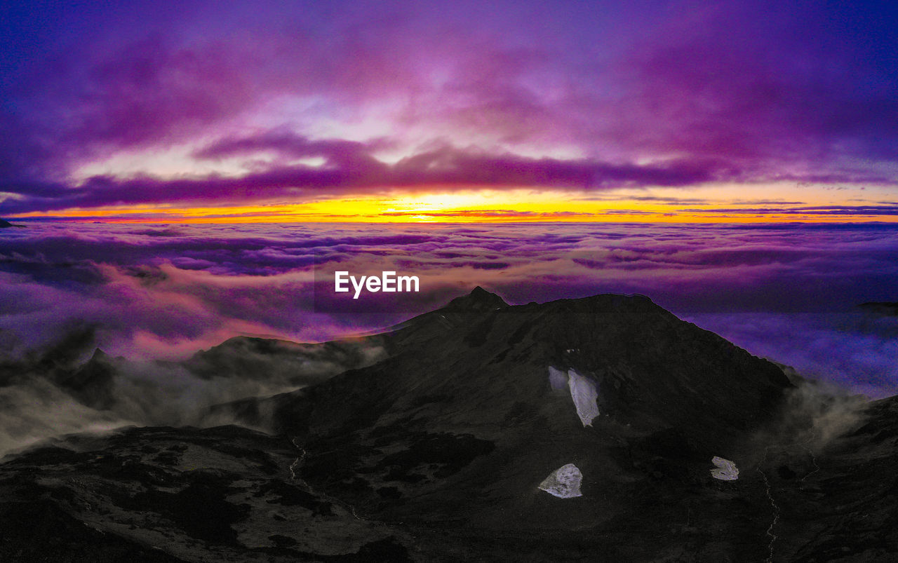 SCENIC VIEW OF MOUNTAIN AGAINST DRAMATIC SKY DURING SUNSET
