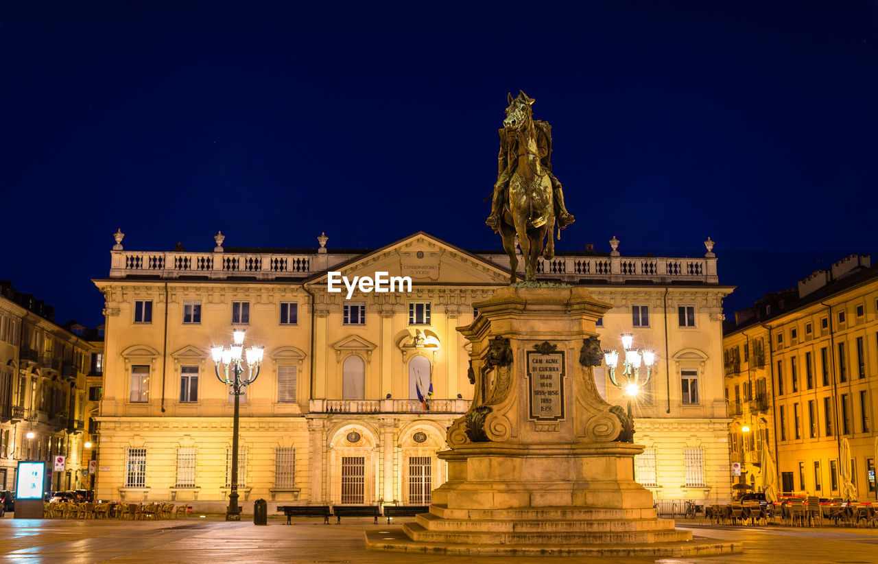 STATUE OF ILLUMINATED BUILDING AT NIGHT