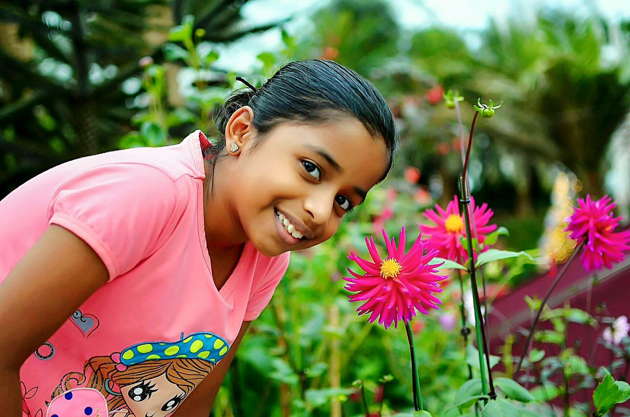 CLOSE-UP PORTRAIT OF A SMILING GIRL IN PINK PARK