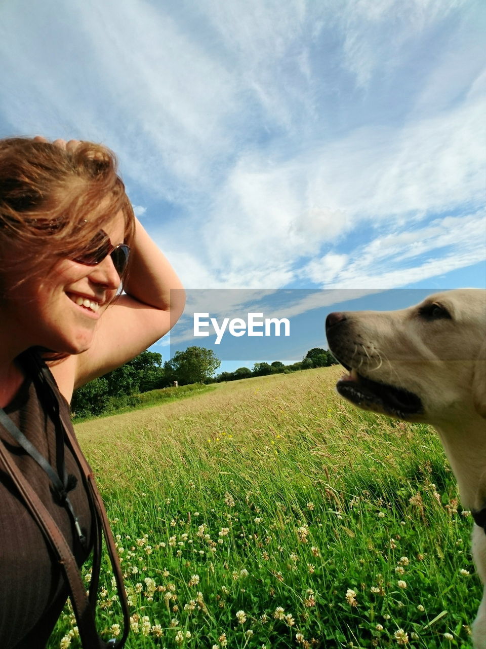 Happy woman face to face with dog on field