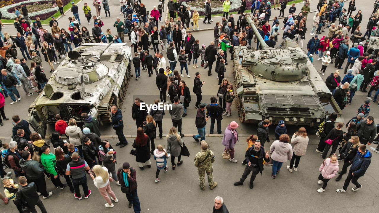 High angle view of people walking on street next to the wrecked russian fascist equipment