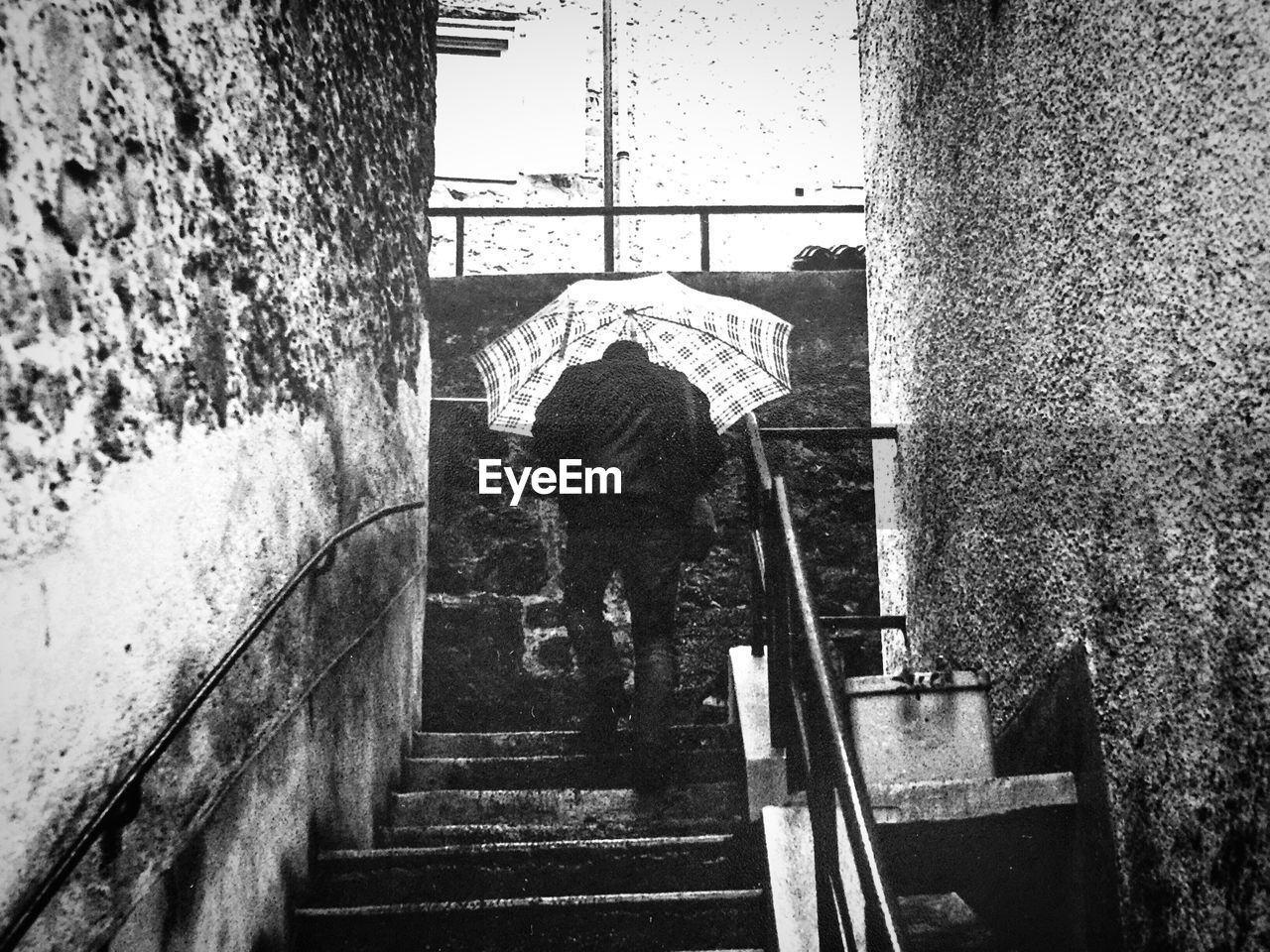 REAR VIEW OF MAN ON RAILING AT RAILWAY STATION