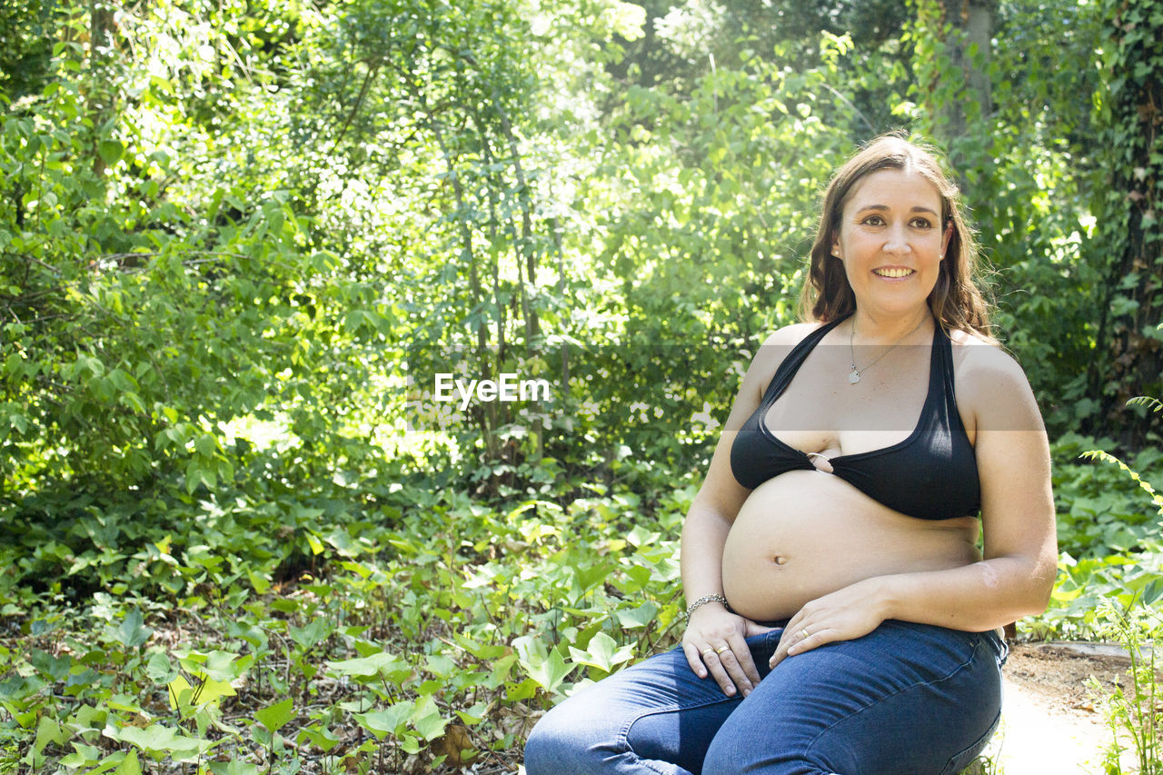 Seven month pregnant woman in a park dressed in jeans