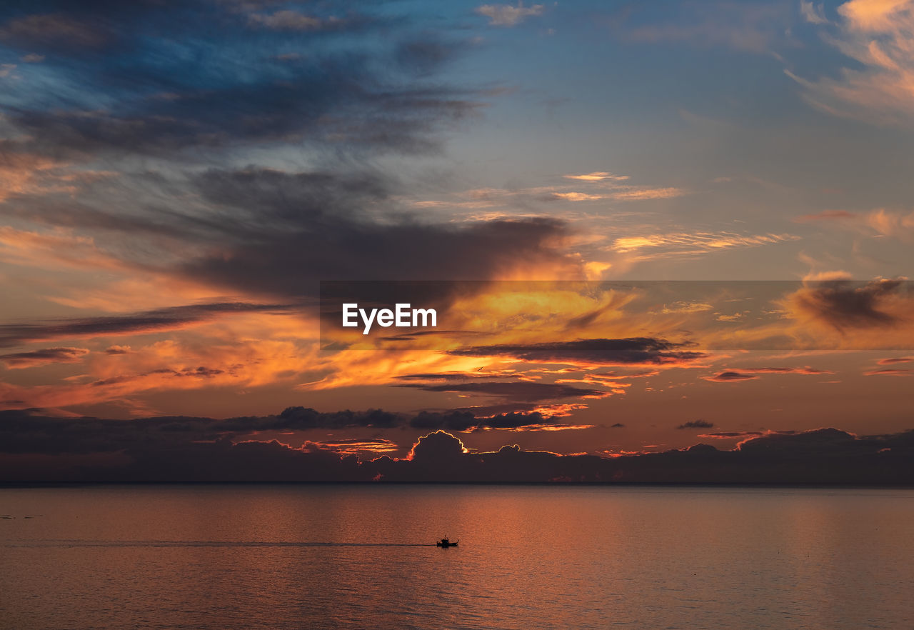 Scenic view of sea against dramatic sky during sunset
