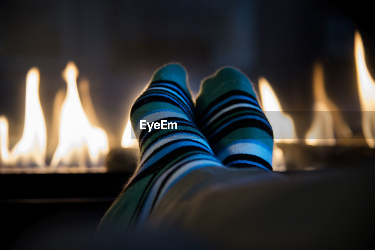 Low section of person wearing socks by fireplace