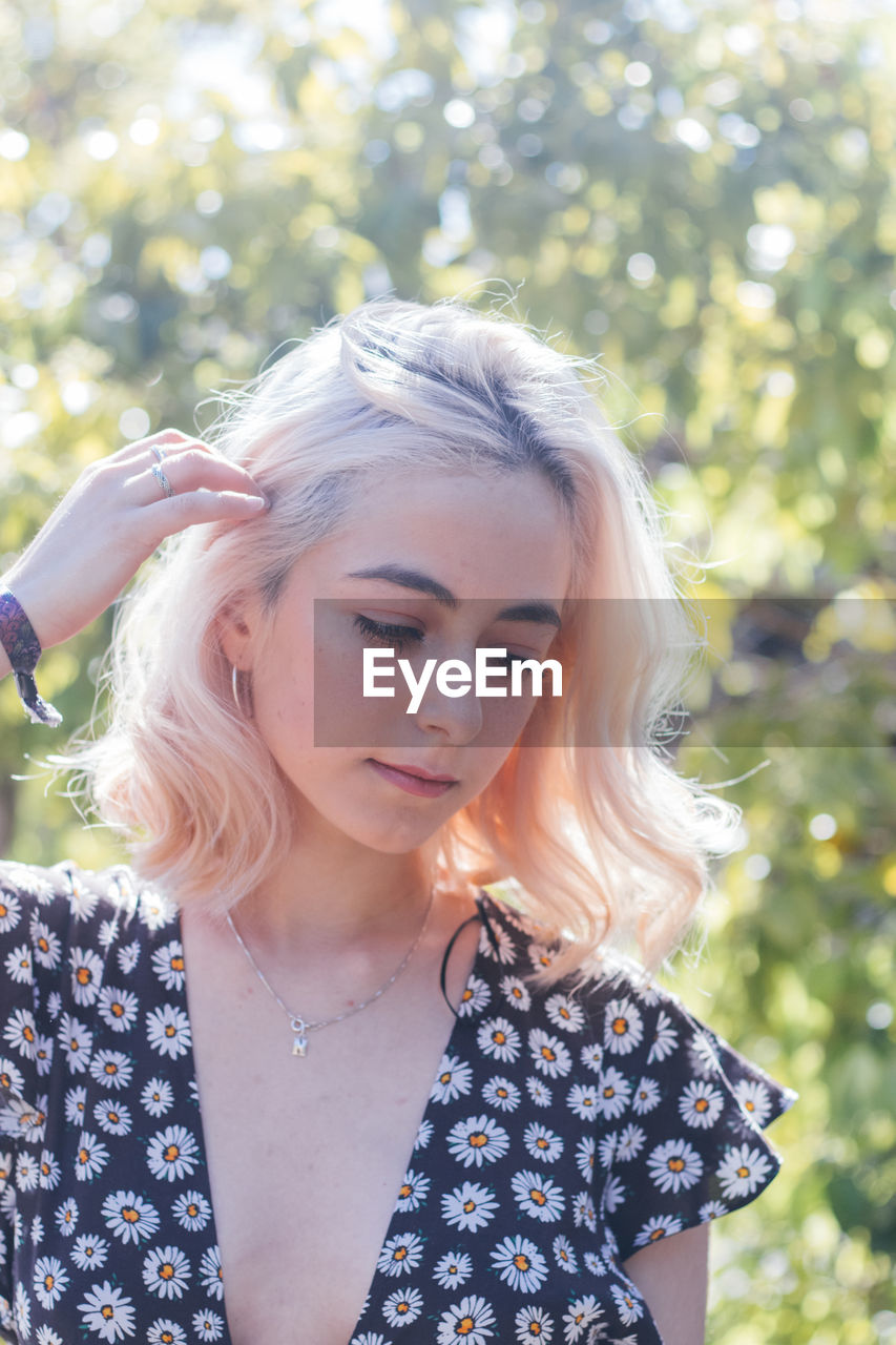 Beautiful young woman looking away against tree