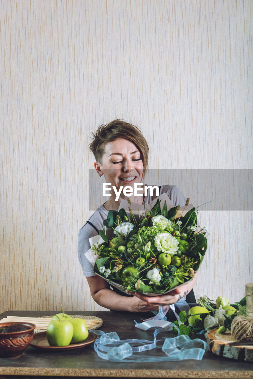 Young woman holding flower arrangement at home