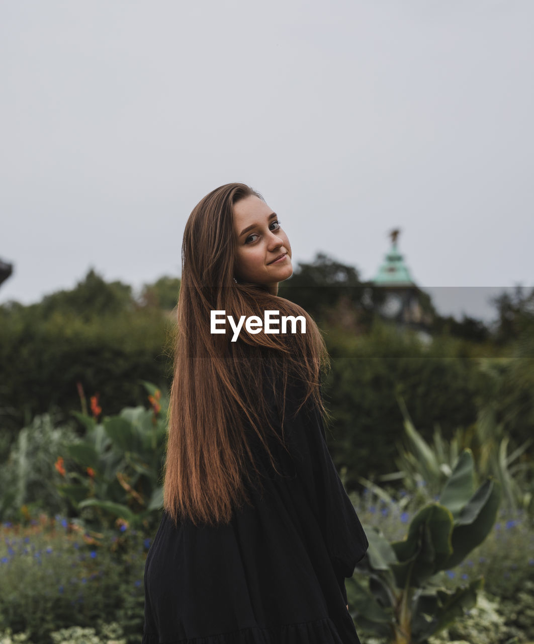 Portrait of smiling young woman standing against sky