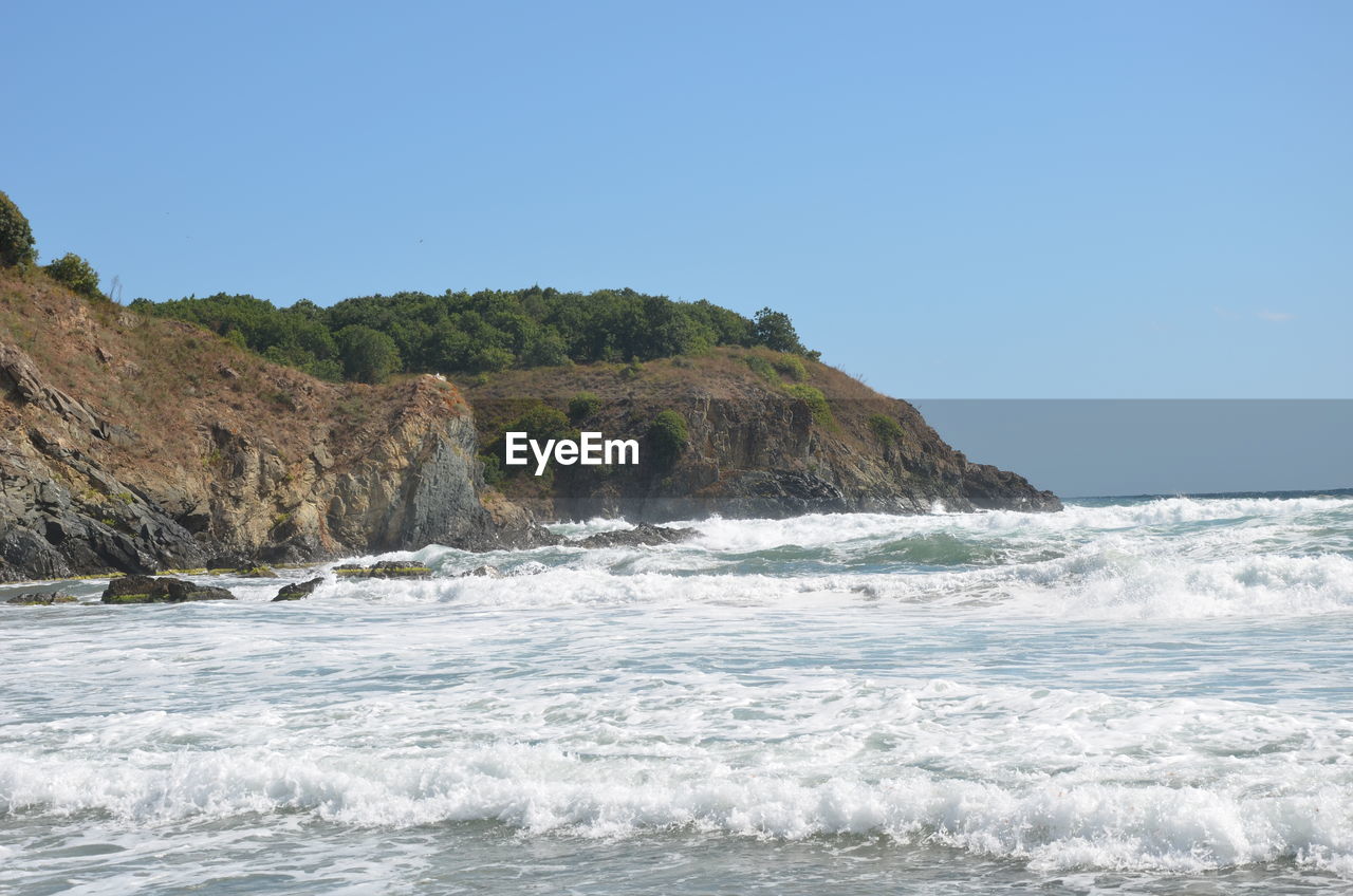 SCENIC VIEW OF ROCKY SHORE AGAINST CLEAR SKY