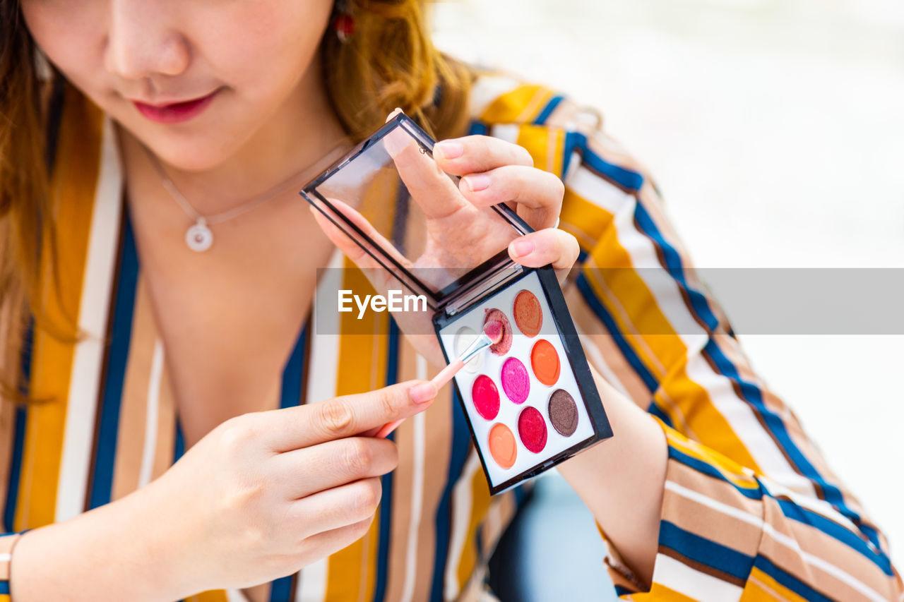 Midsection of woman holding beauty product 