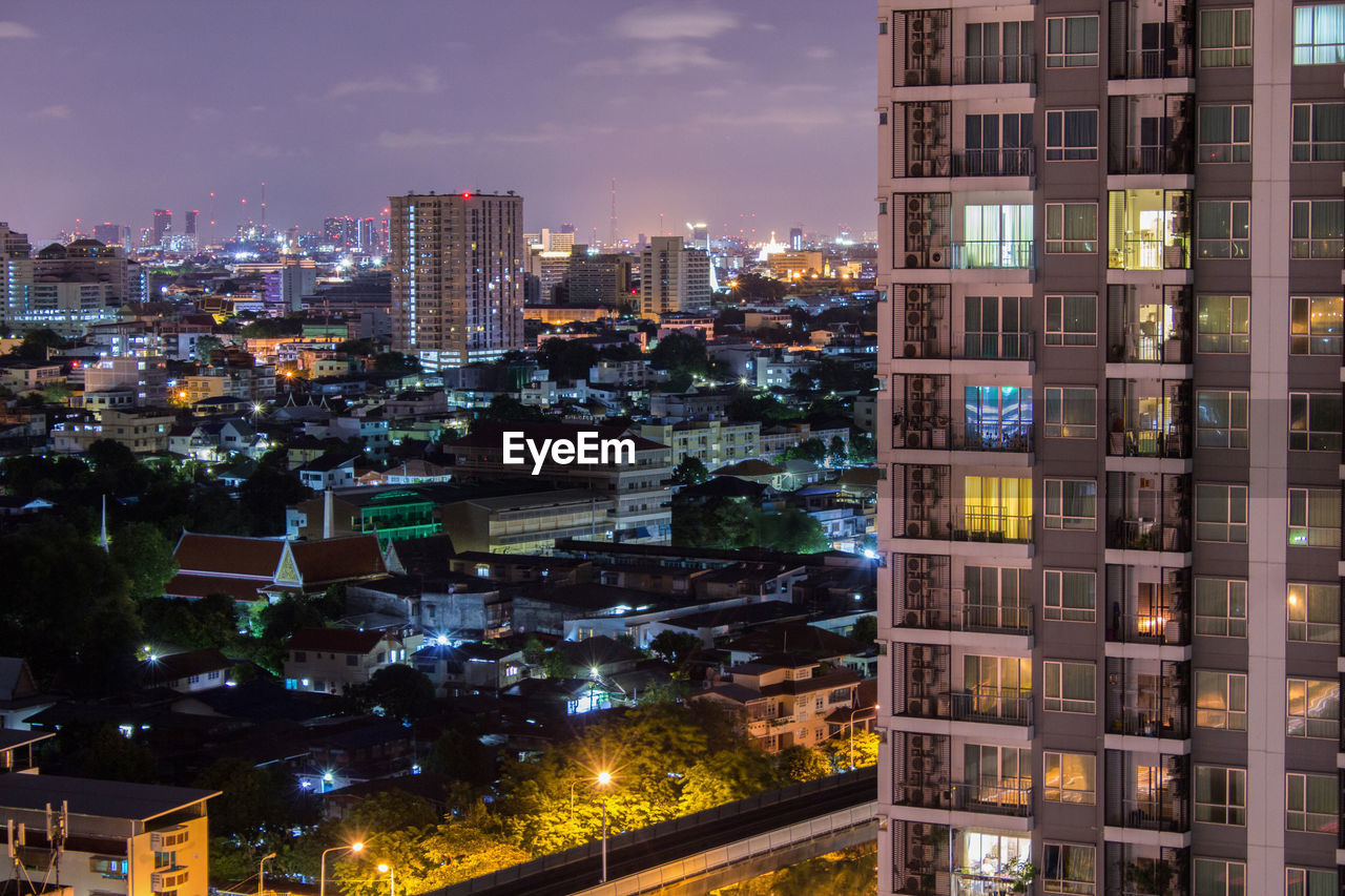 Illuminated buildings in city against sky at night