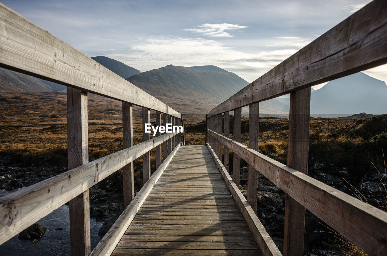 Empty footbridge against mountains