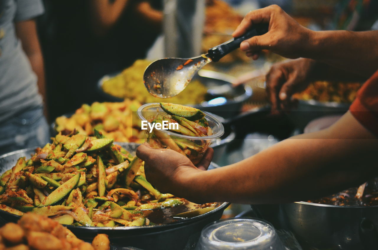 Cropped hands filling bowl with pickle in market