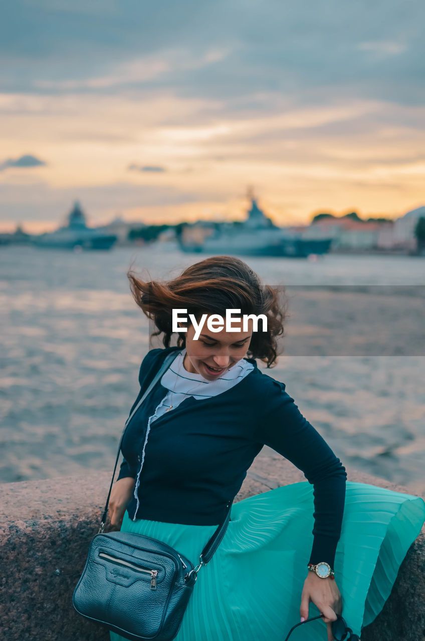 SMILING WOMAN SITTING ON BEACH