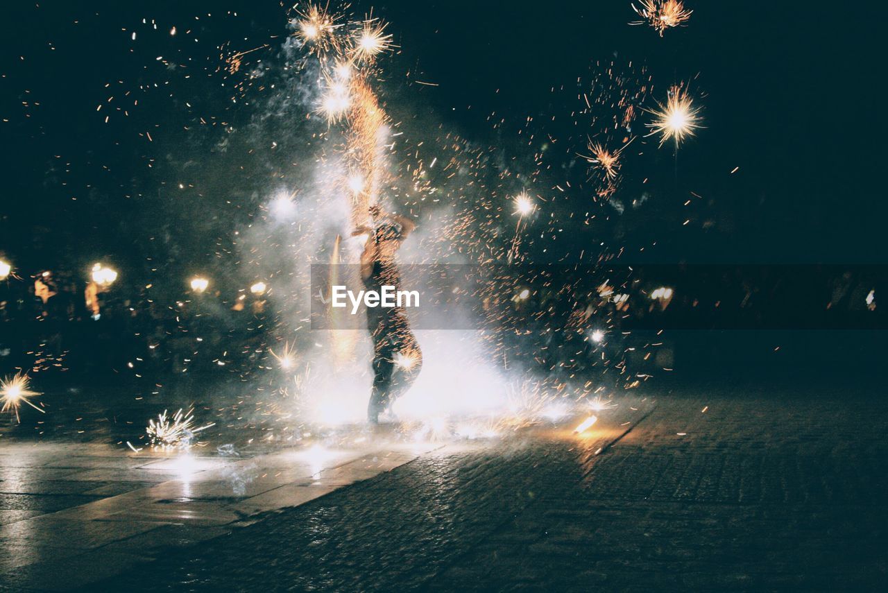 Man standing amidst fireworks at night