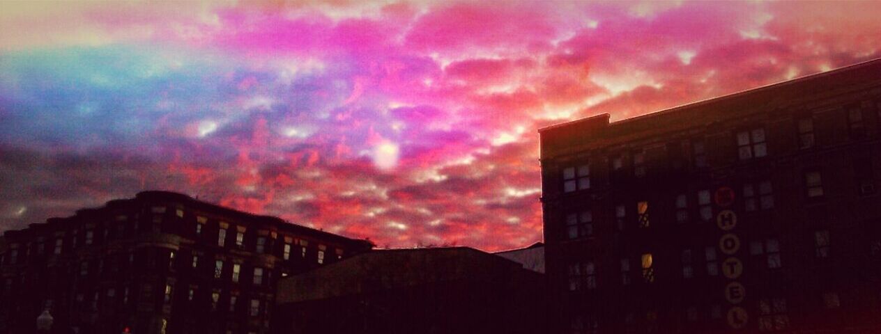 LOW ANGLE VIEW OF BUILDINGS AGAINST CLOUDY SKY AT SUNSET