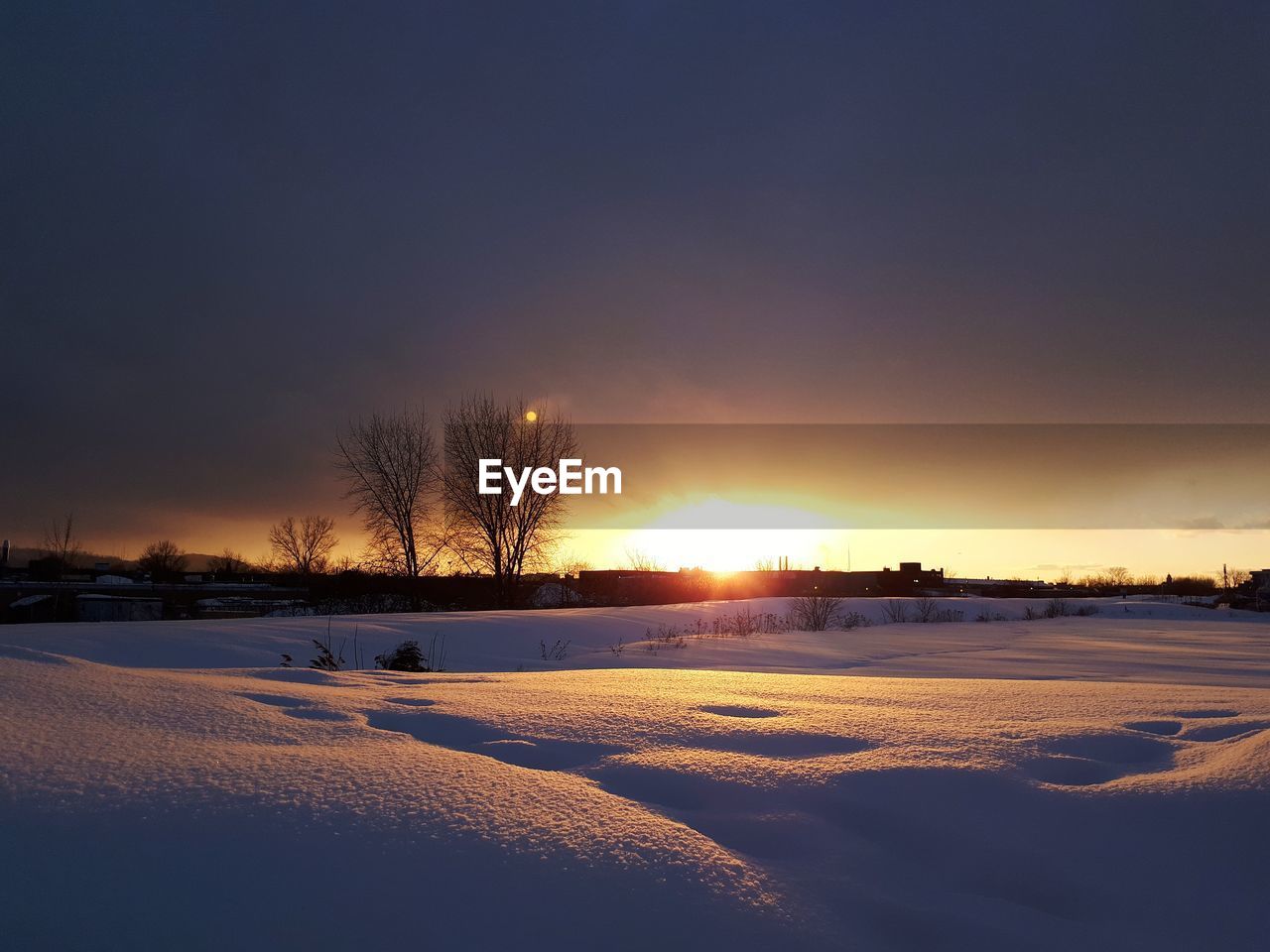 SCENIC VIEW OF SNOWY FIELD AGAINST SKY DURING SUNSET